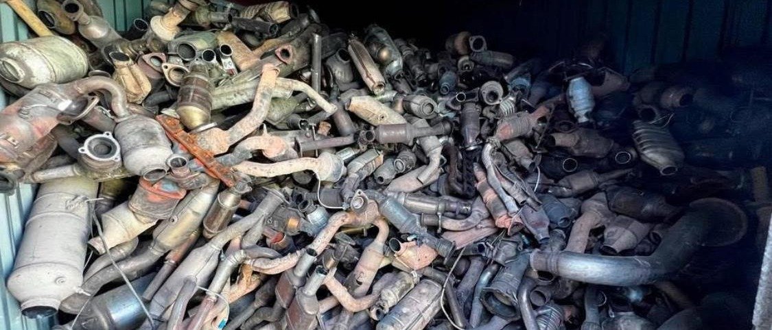 A shipping container packed with spent catalytic converters and exhaust assemblies