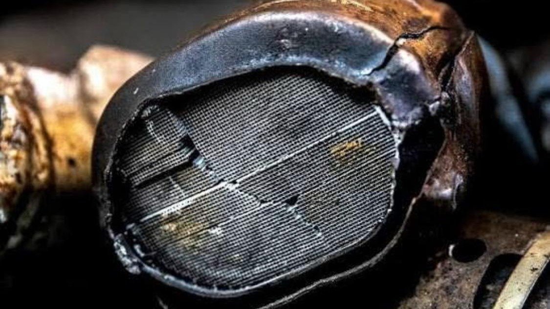 A spent catalytic converter cut open, the coated honeycomb substrate exposed inside the steel shell