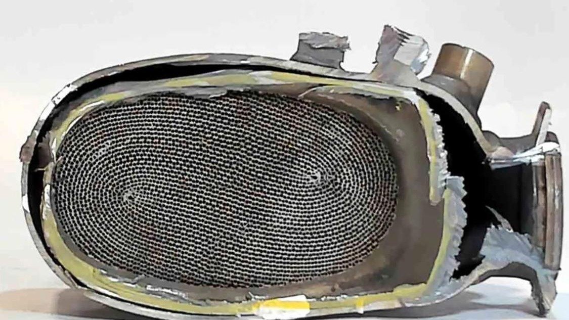 A catalytic converter sectioned lengthways, showing the ceramic honeycomb and the mat that holds it in the shell